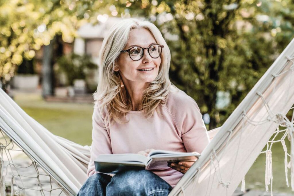 woman sitting on hammock with a book